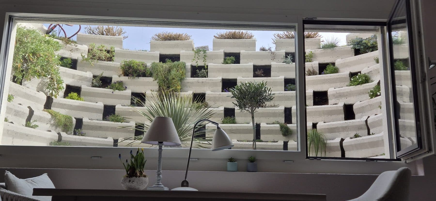 Lernstudio mit Blick durch das Fenster auf eine begrünte Betonfassade