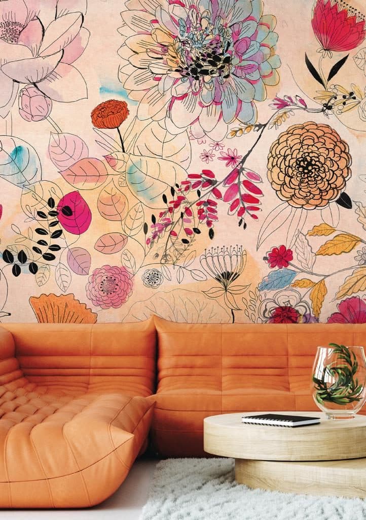 Sitzecke mit orangenem Sofa vor floraler Wandgestaltung